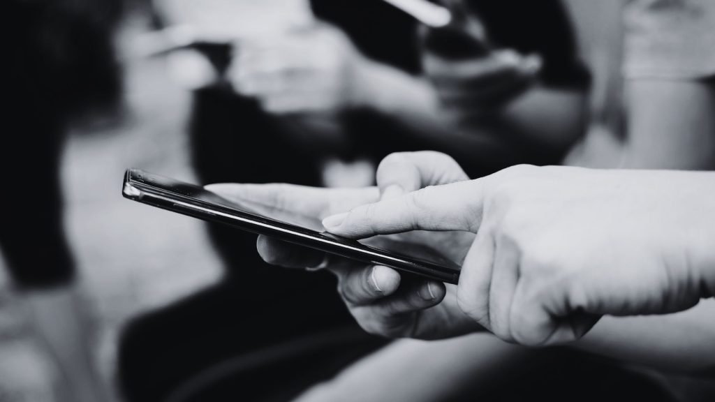 Why Consistent Content Marketing Still Wins for Small Businesses - black and white photo of people sitting side by side on their phones