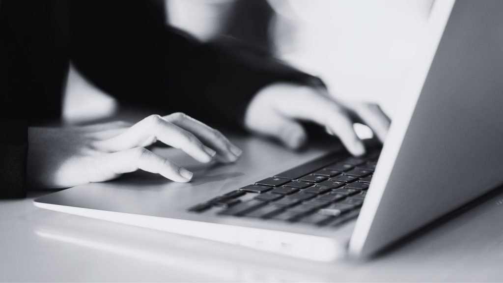 How to Lead a Sales Conversation That Closes - Black and white hand typing on a keyboard