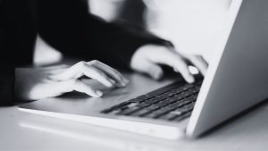 How to Lead a Sales Conversation That Closes - Black and white hand typing on a keyboard